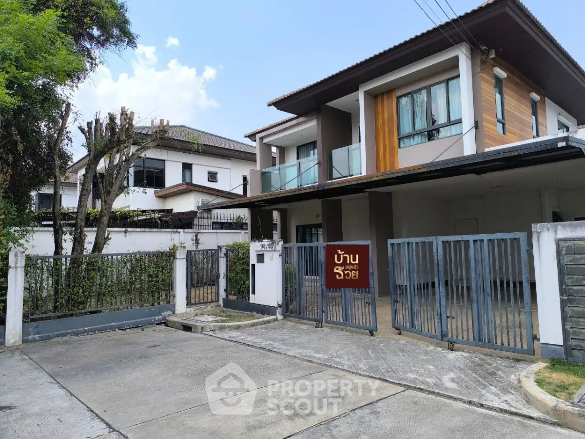 Modern two-story house with gated entrance and driveway in a suburban neighborhood.