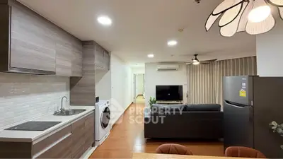 Modern open-plan living room with kitchen, featuring sleek appliances and stylish decor.