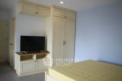 Cozy bedroom with built-in wardrobe and TV, perfect for modern living.