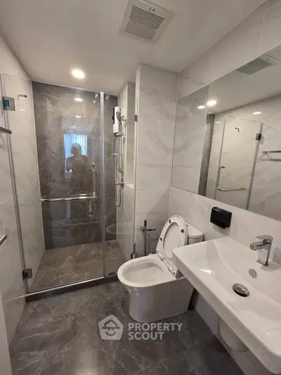 Modern bathroom with sleek design, featuring a glass shower enclosure and contemporary fixtures.