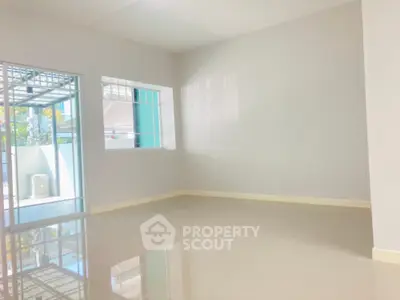 Spacious and sunlit empty room with glossy tiled flooring and large windows offering ample natural light, perfect for a versatile living space.
