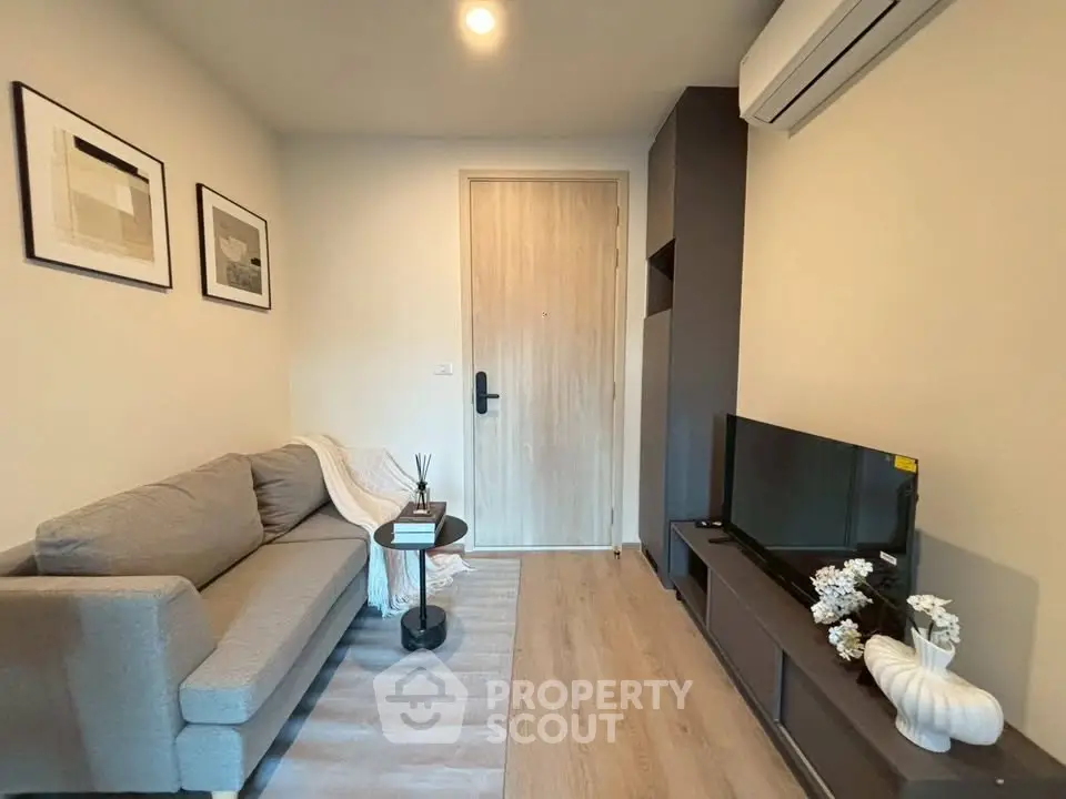 Modern living room with cozy sofa, stylish decor, and wall-mounted TV in a compact apartment.