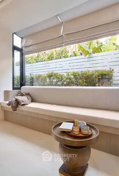 Stylish modern living room with large window and cozy seating area, perfect for relaxation.