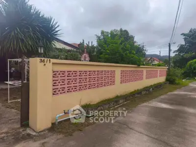 Charming residential property with unique pink lattice wall and lush greenery.
