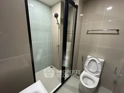 Modern bathroom with glass shower and sleek fixtures in contemporary apartment.