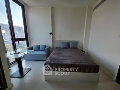 Modern bedroom with large windows and city view, featuring a cozy bed and stylish seating area.