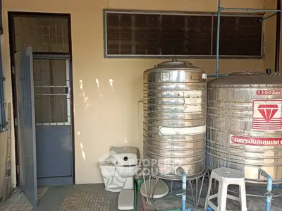 Utility area with water tanks and toilet in a residential property
