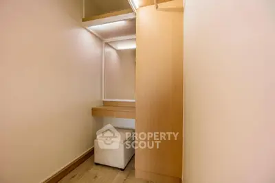 Spacious walk-in closet with modern wooden finishes and seating area.