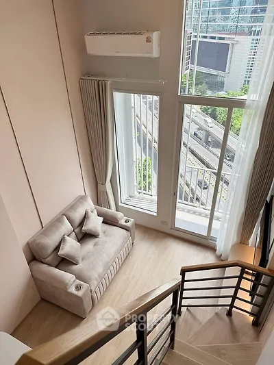 Modern loft apartment with large windows and cozy seating area, offering stunning city views.