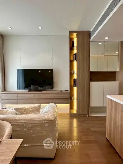 Modern living room with sleek TV unit and cozy seating area, featuring elegant wooden flooring.