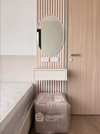 Modern bedroom with stylish wooden accents and oval mirror, showcasing minimalist design and cozy atmosphere.