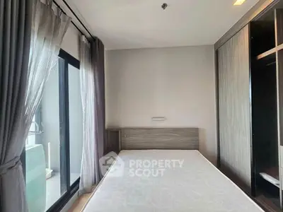 Modern bedroom with large window and balcony access in a stylish apartment.