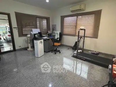 Spacious home office with treadmill and modern furnishings, ideal for work and fitness enthusiasts.