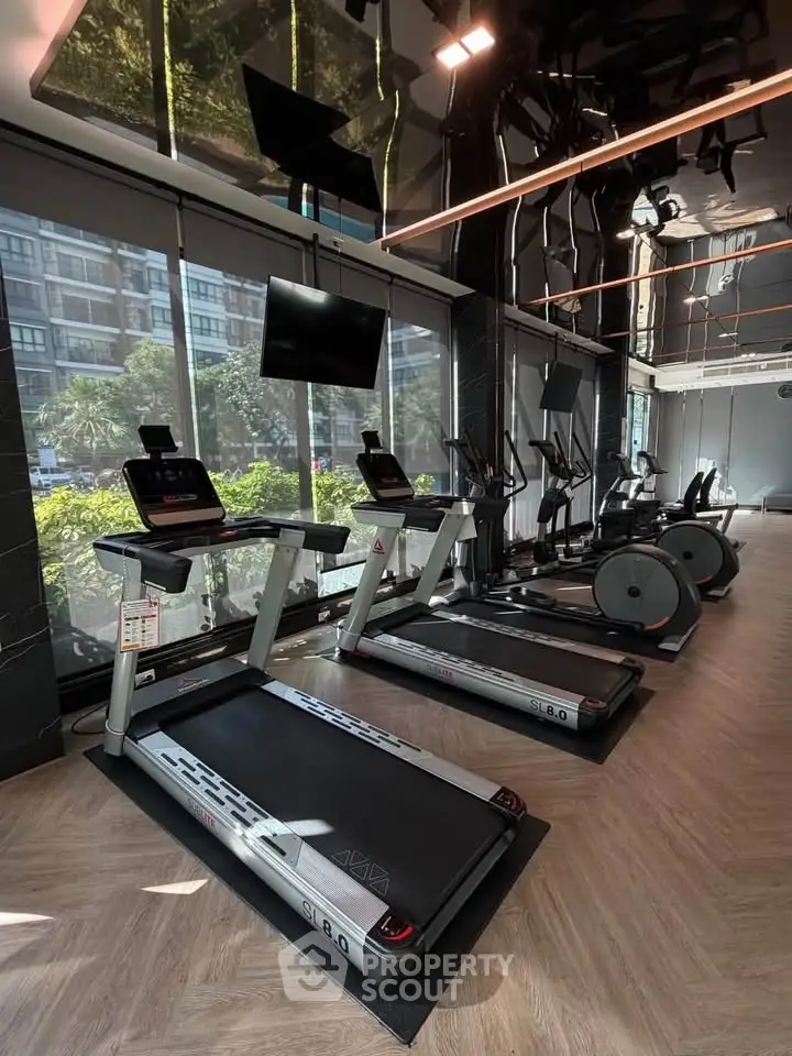Modern gym with treadmills and exercise bikes in a sleek building.