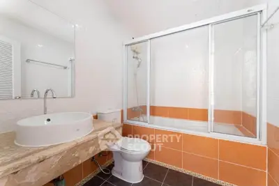 Modern bathroom with orange tiles and glass shower enclosure