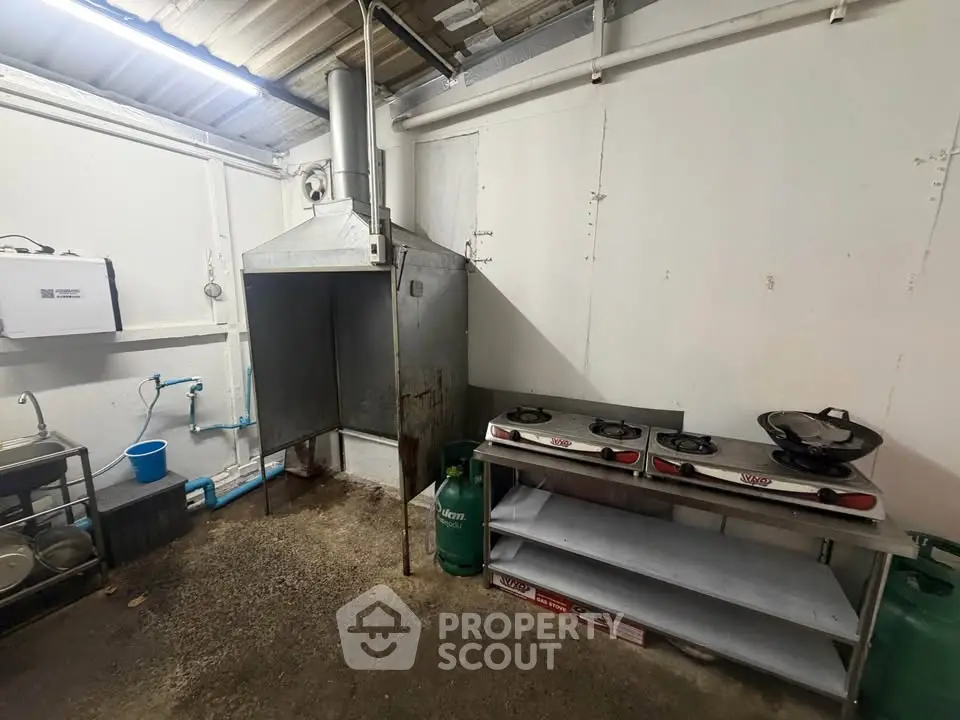 Industrial kitchen space with gas stoves and ventilation system, ideal for commercial use.
