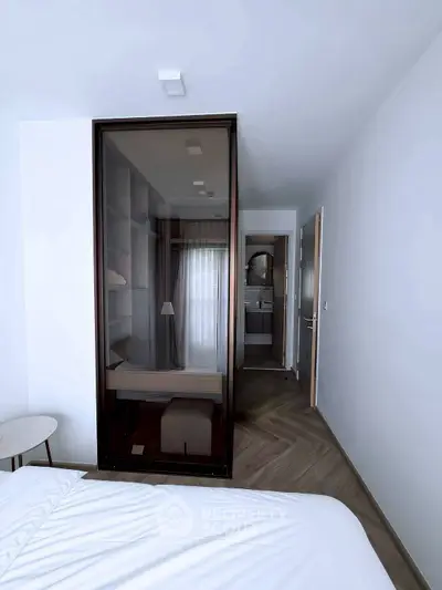 Modern bedroom with glass wardrobe and ensuite bathroom, featuring sleek design and natural light.