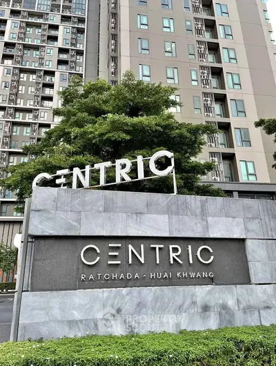 Modern high-rise building exterior with Centric Ratchada Huai Khwang signage and lush greenery.