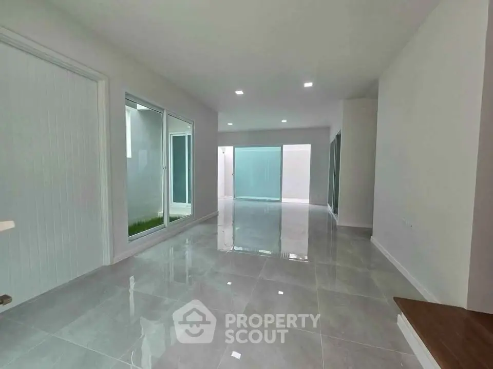Spacious modern living room with large windows and glossy tiled floors