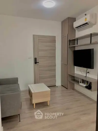 Modern living room with sleek furniture and wall-mounted TV in a cozy apartment.