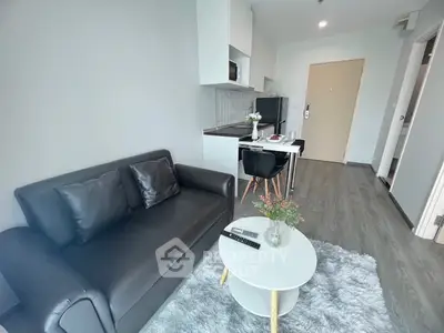 Modern living room with sleek black sofa and compact kitchen area