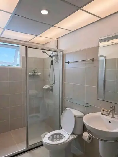 Modern bathroom with glass shower, sleek fixtures, and neutral tiles.