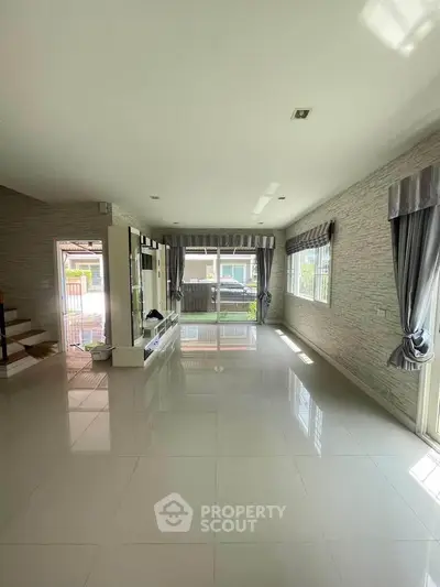 Spacious living room with large windows and modern tile flooring