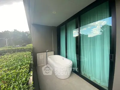 Luxurious balcony with standalone bathtub and lush garden view
