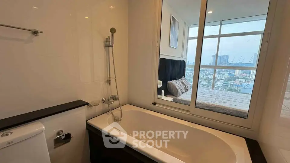 Modern bathroom with bathtub and window view into a stylish bedroom