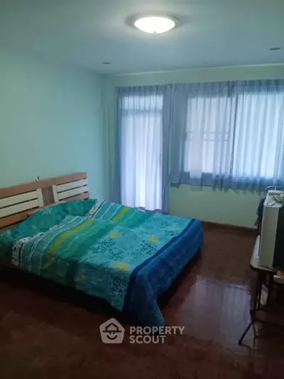 Cozy bedroom with wooden flooring and large windows for natural light.