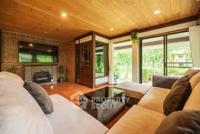 Spacious living room with cozy seating and large windows overlooking greenery.