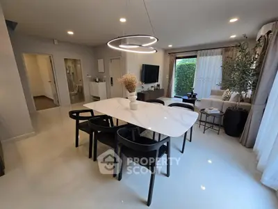 Modern dining area with elegant marble table and stylish lighting in open-plan living space.