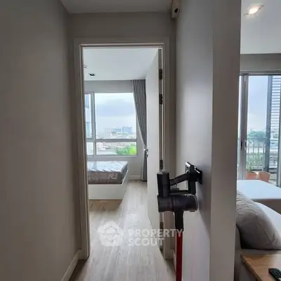 Modern apartment hallway leading to a bright bedroom with city view.