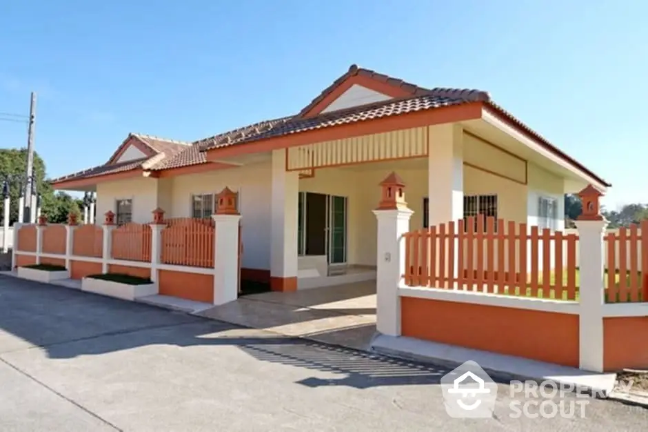 Charming single-story house with orange accents and fenced yard in sunny neighborhood.