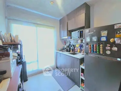 Cozy kitchen with modern appliances and ample storage space, featuring a sleek fridge and large window for natural light.