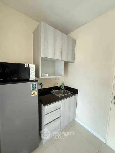 Compact modern kitchen with sleek cabinetry and stainless steel appliances in a cozy apartment.