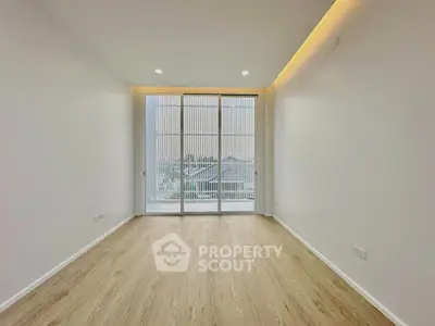 Spacious modern living room with large windows and wooden flooring, offering ample natural light and a serene ambiance.