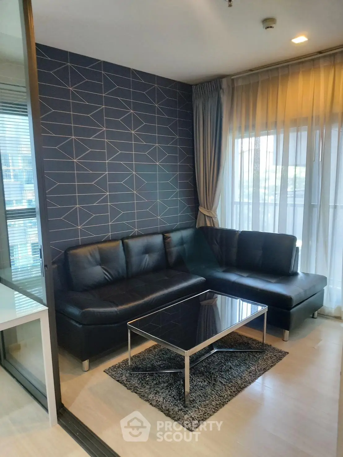 Modern living room with stylish geometric wallpaper and sleek black leather sofa