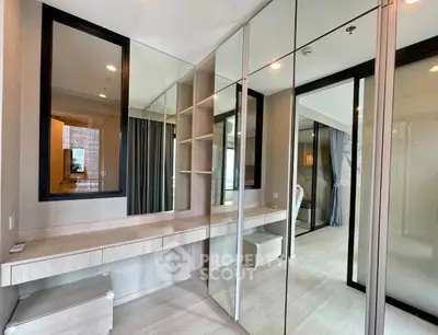 Modern bedroom with mirrored wardrobe and built-in desk, featuring sleek design and ample storage space.