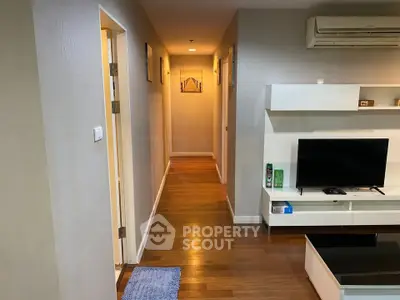 Modern apartment hallway with wooden flooring and sleek TV setup