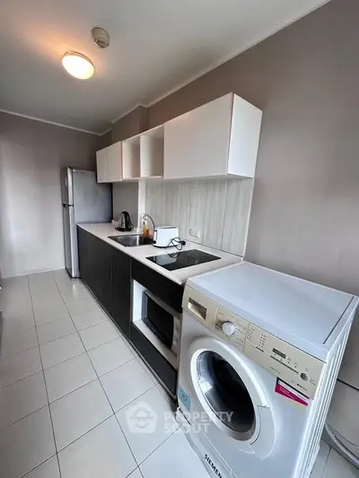Modern kitchen with sleek appliances and washing machine in compact layout.