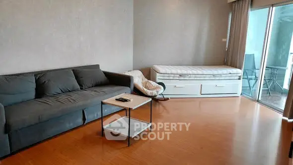 Spacious living room with modern sofa and daybed, featuring a sleek wooden floor and balcony access.