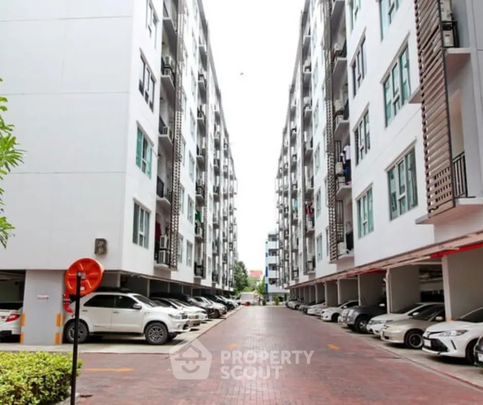 Modern apartment complex with spacious parking area and sleek architecture.