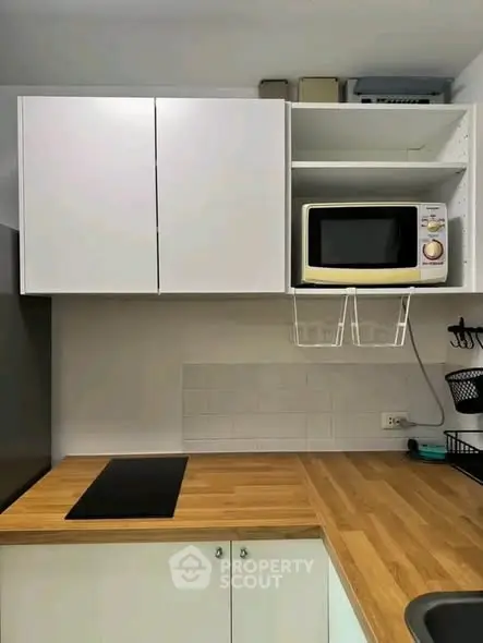 Modern kitchen with sleek cabinetry and built-in microwave, featuring a minimalist design and wooden countertops.