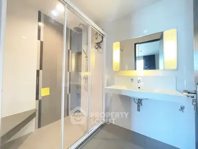 Modern bathroom with glass shower and sleek vanity in a contemporary home.