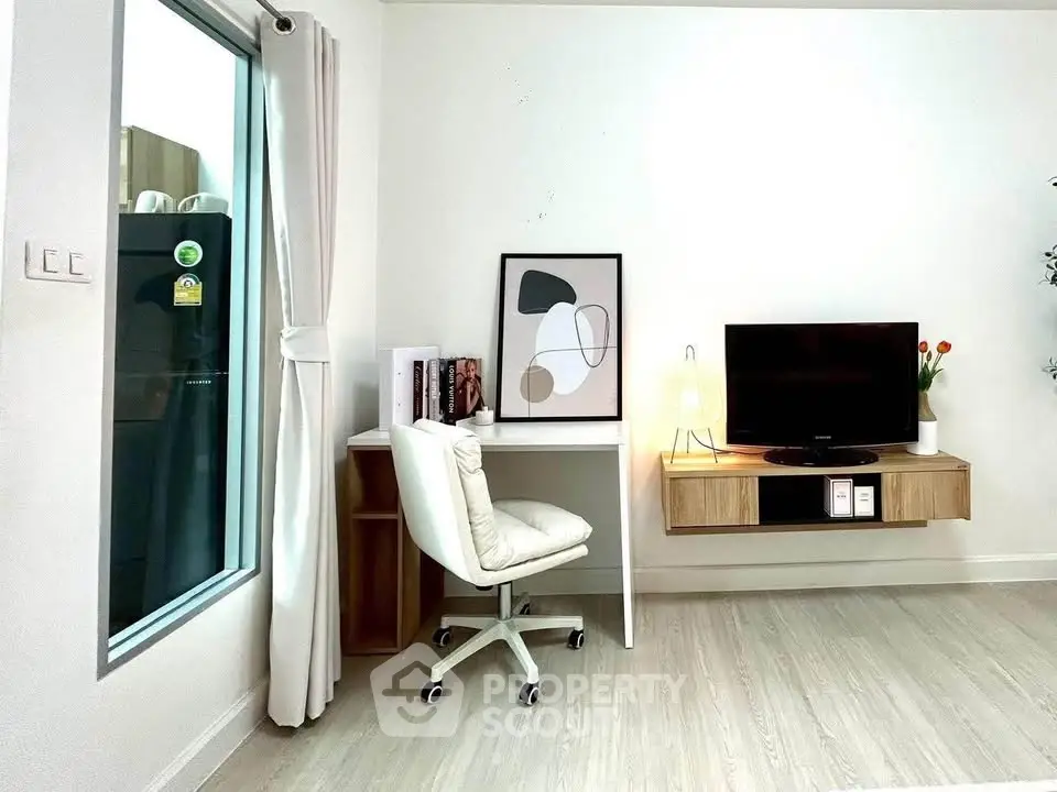 Modern study area with sleek desk, chair, and wall-mounted TV in stylish apartment.
