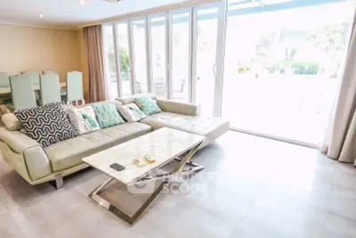Spacious living room with modern sofa and large glass doors opening to a bright outdoor area.