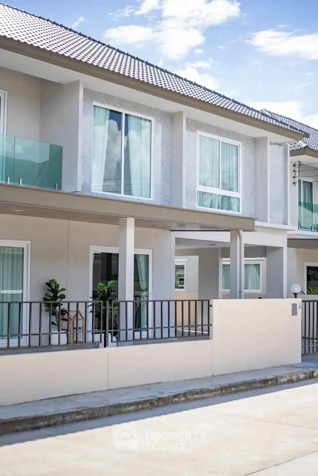 Modern townhouse exterior with glass balconies and sleek design in a serene neighborhood.