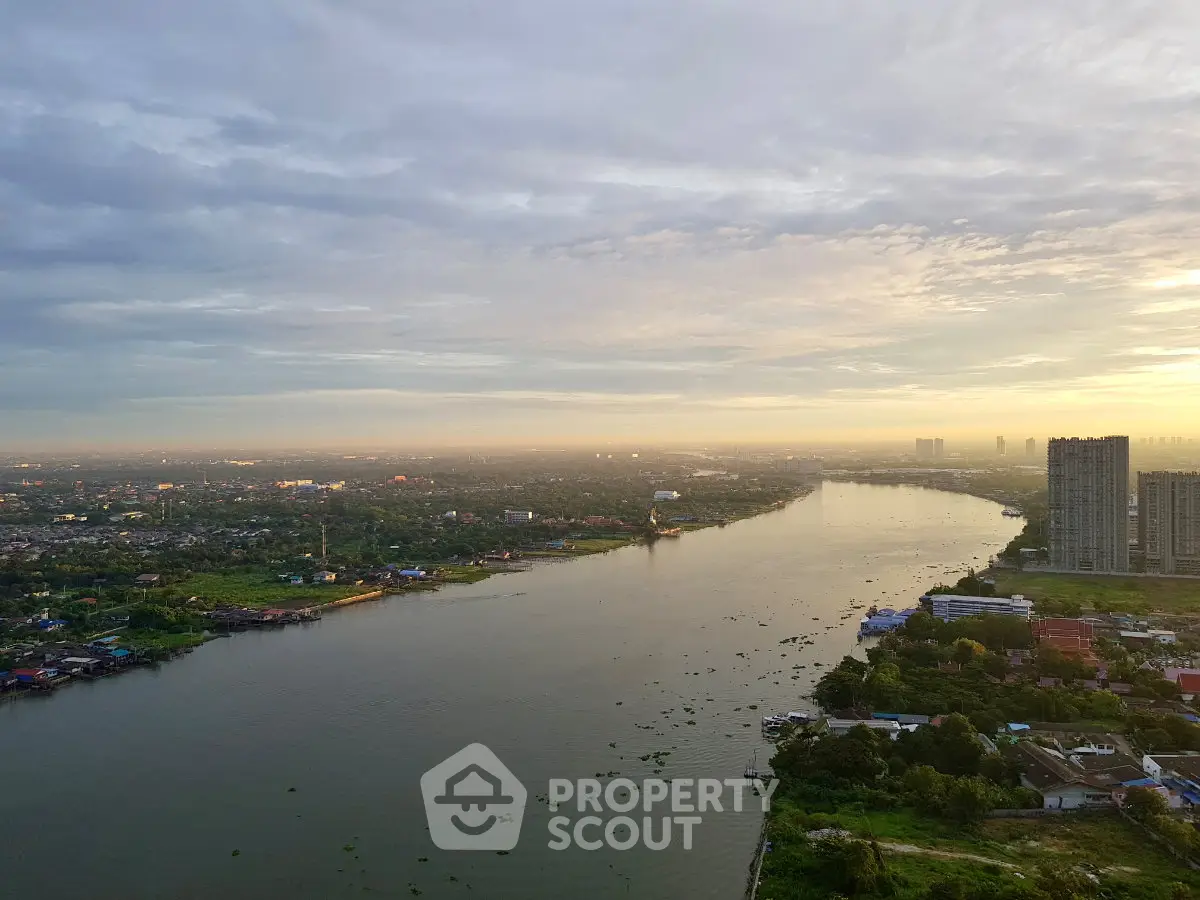 Stunning river view from high-rise building at sunrise, showcasing expansive cityscape and serene waterway.