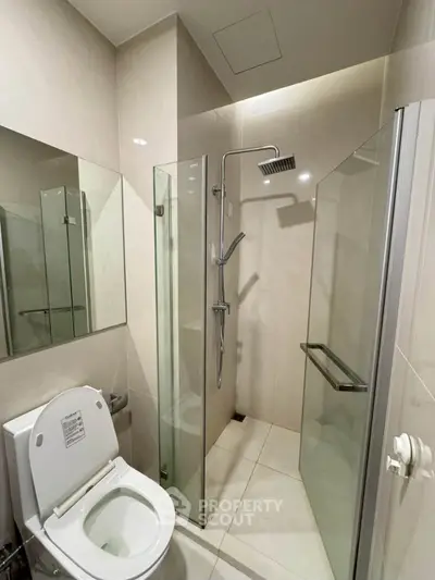 Modern bathroom with glass shower enclosure and sleek fixtures in a contemporary apartment.